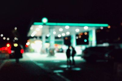 Defocused image of illuminated walking on street at night