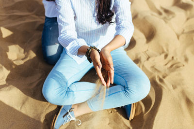 Low section of woman sitting on sand