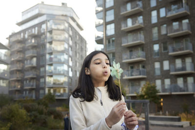 Girl blowing on pinwheel outdoors