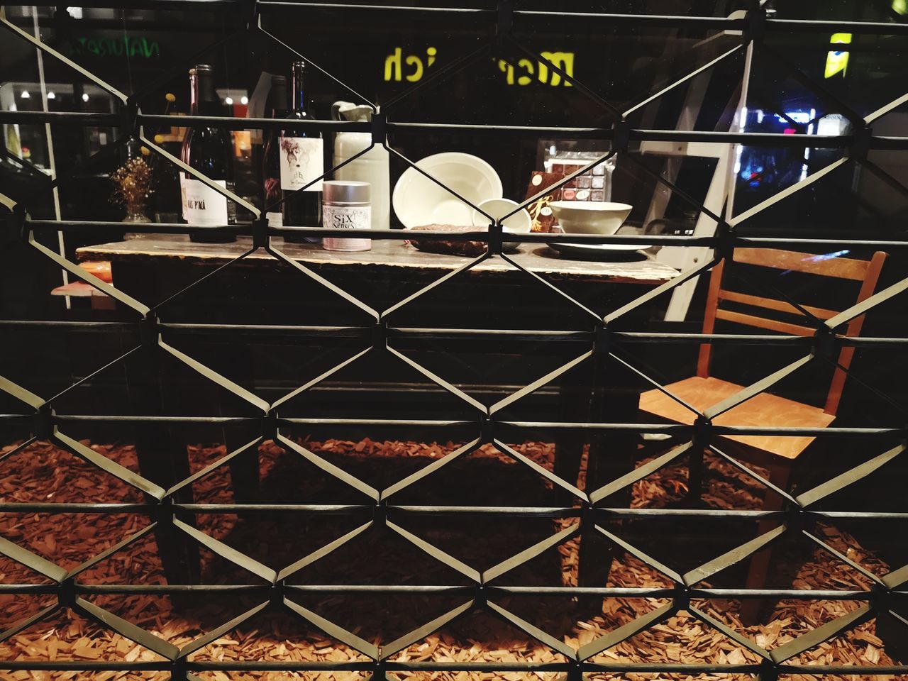 FULL FRAME SHOT OF CHAINLINK FENCE WITH ILLUMINATED METAL STRUCTURE