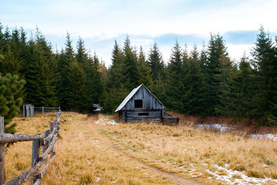 House on field by trees against sky