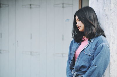 Beautiful young woman standing against wall