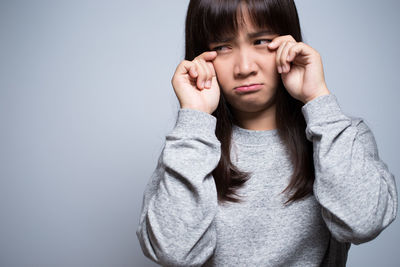 Sad young woman against gray background