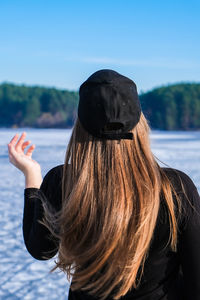 Young female woman back to the camera with long hair in a snow landscape. happy hipster girl