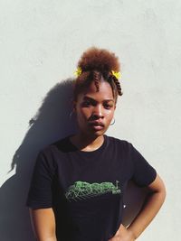 Portrait of young woman standing against wall