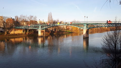 Arch bridge over river against sky in city