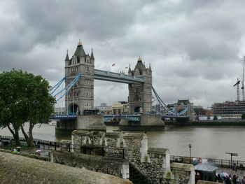 Low angle view of tower bridge over thames river against cloudy sky