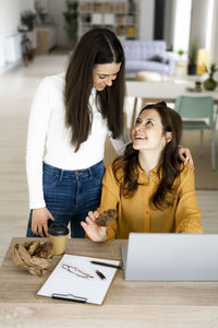 Smiling young woman using smart phone on table