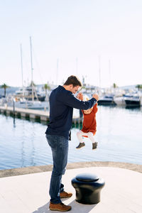 Young man standing on pier at harbor