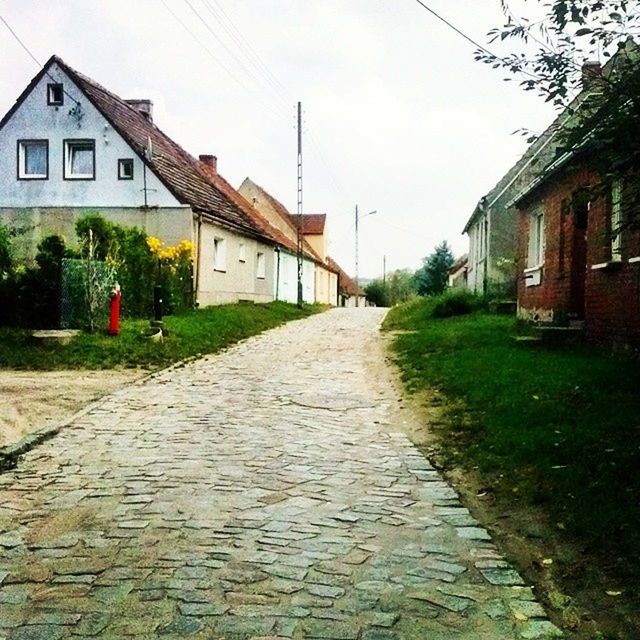 building exterior, architecture, built structure, the way forward, house, diminishing perspective, residential structure, cobblestone, vanishing point, walkway, residential building, street, pathway, narrow, grass, footpath, plant, sky, day, outdoors