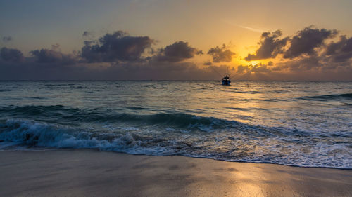 Silhouette man in sea against sky during sunset