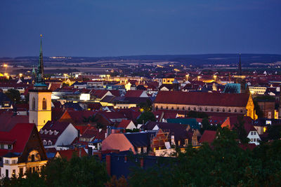 High angle view of illuminated buildings against blue sky