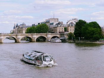 Boat on bridge over river in city against sky