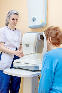 A girl optometrist examines the eyes of a patient using special modern equipment