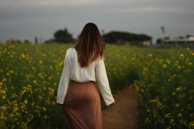 Rear view of woman walking on footpath amidst plants