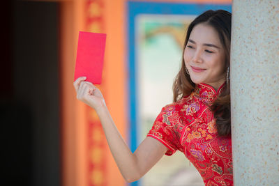 Young woman smiling while standing against wall