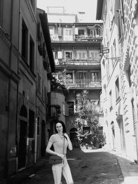 Woman standing in alley amidst buildings in city