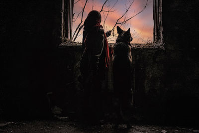 Rear view of woman with dog standing against sky