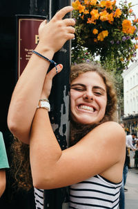 Cheerful young woman hugging lamp post