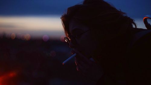 Close-up of woman smoking during night outdoors