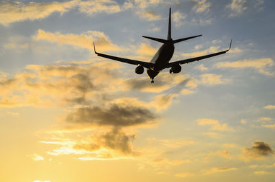 Low angle view of airplane flying against sky during sunset