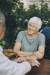 Smiling senior woman looking at partner while sitting at restaurant in city