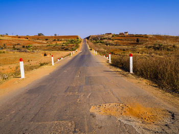 Road amidst field against clear sky