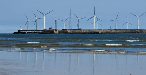 Wind turbines on beach against sky