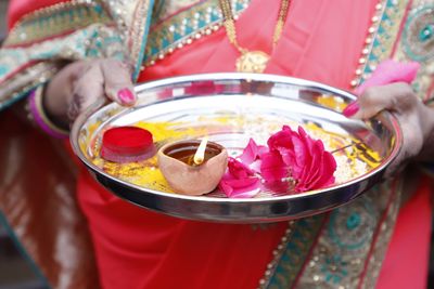 Midsection of woman holding plate with decoration during traditional ceremony