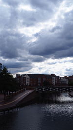 Buildings by river against sky in city