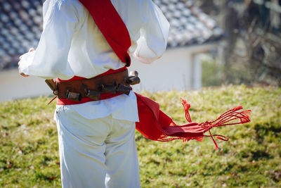 Midsection of man holding umbrella while standing on field