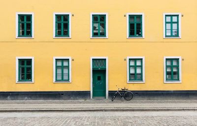 Bicycle parked against yellow building