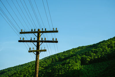 Low angle view of telephone pole against clear blue sky