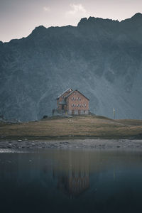 Built structure by lake and mountains against sky