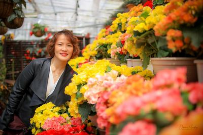 Portrait of smiling mature woman standing by colorful flowers in shop