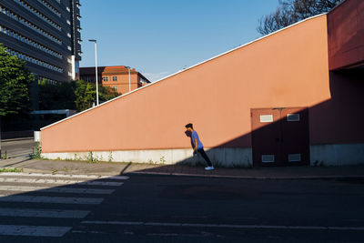 Young man leaning by wall in city