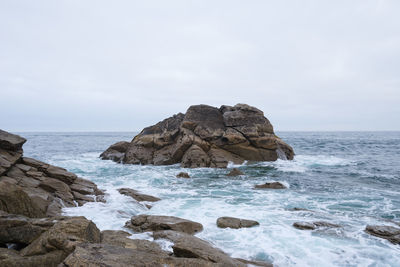 Rock formations on shore against sky