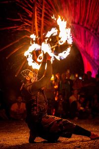 Side view of male fire dancer dancing on field at night