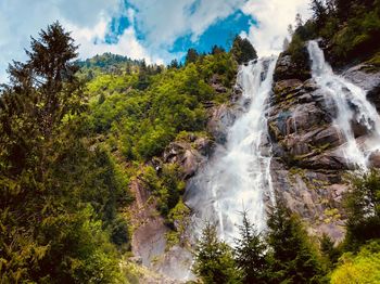 Scenic view of waterfall in forest against sky