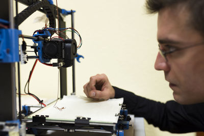 Confident engineer examining 3d printer on table