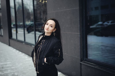 Portrait of young woman standing in city during winter