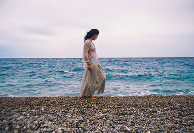 Woman on beach by sea against sky