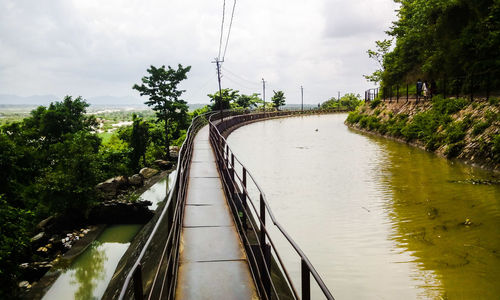 Footbridge over river against sky
