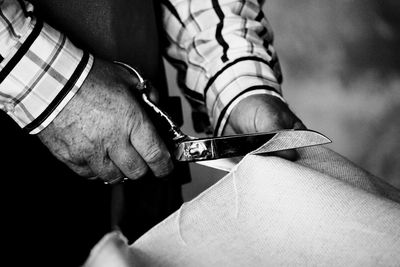 Close-up of man's hand cutting textile