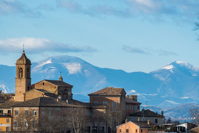 Buildings against sky with mountain range in background