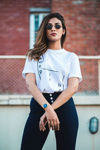 Portrait of young woman wearing sunglasses standing outdoors