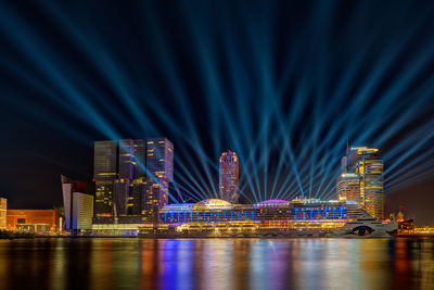 Illuminated buildings at waterfront in city during night