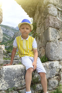 Full length portrait of boy sitting wall