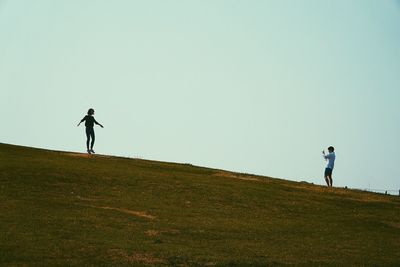 Man walking on grass against clear sky