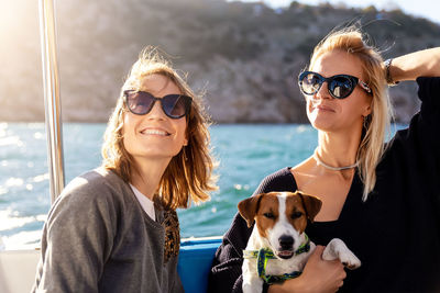 Smiling females with dog standing on boat